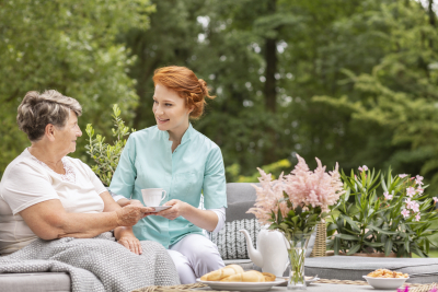 happy nurse giving tea to elderly woman
