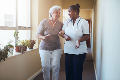 caregiver walking and talking with senior woman